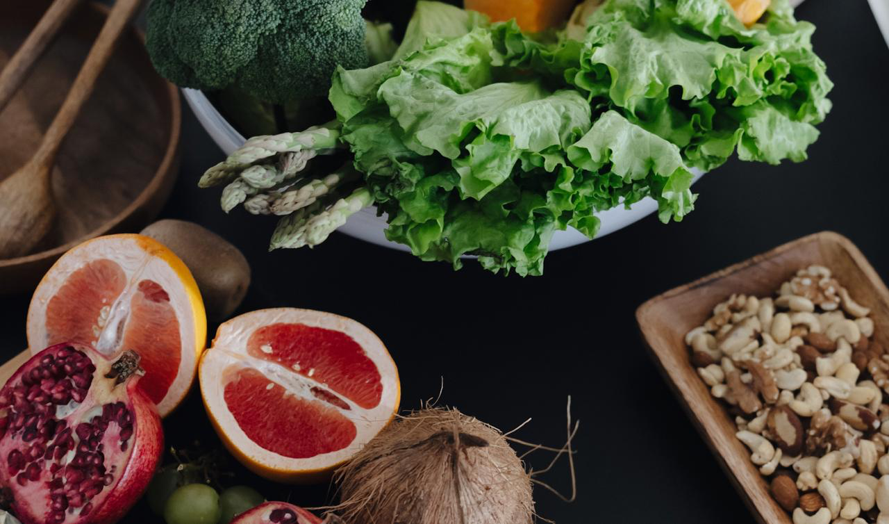 Fresh vegetables, fruits, and nuts on a dark table